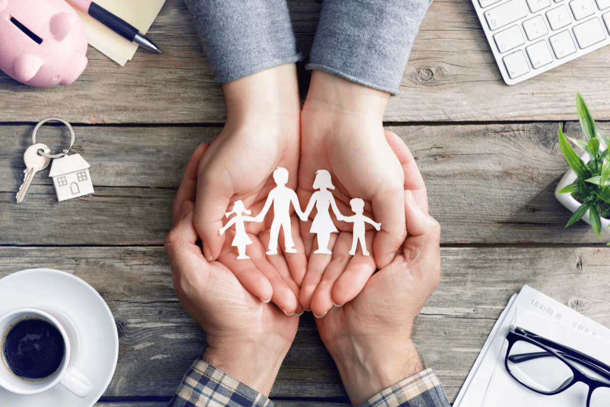 Couples hands holding paper cutout of family